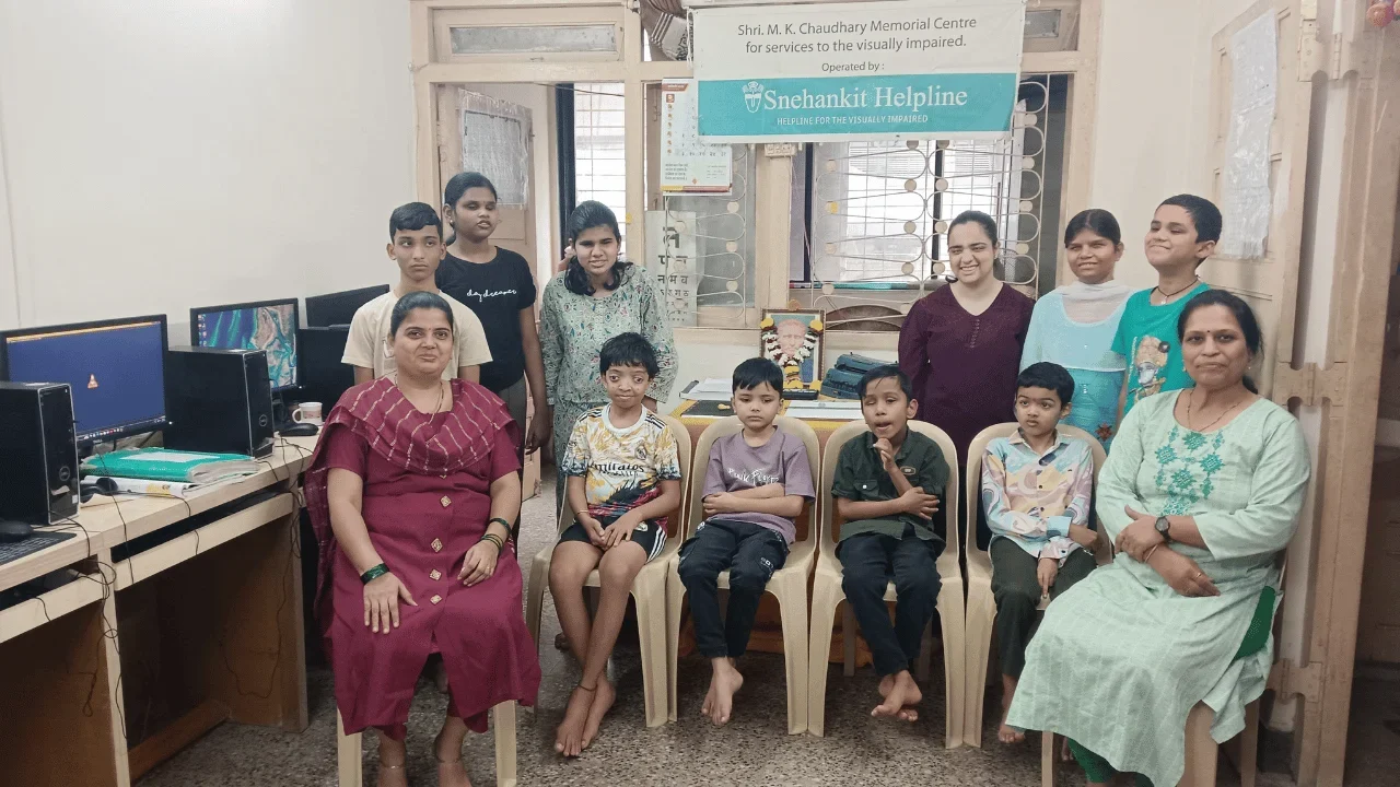 Group photo of beneficiaries and volunteers seated together at Snehankit Helpline centre.